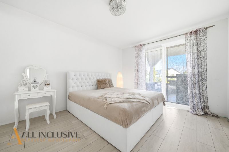 A bedroom in a family house with a bed, a mirrored table, and a floor with a wooden decor.