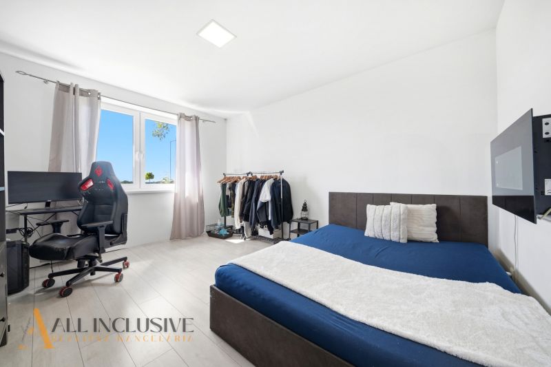 A room in a family house with a bed, a desk, and a wardrobe stand, flooring with a wooden decor.