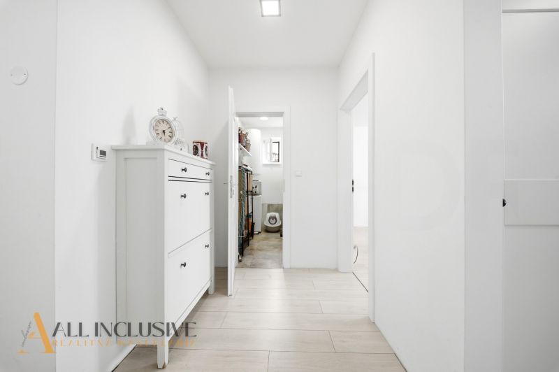 A hallway in a family house with a cabinet, wooden decor flooring, white walls.