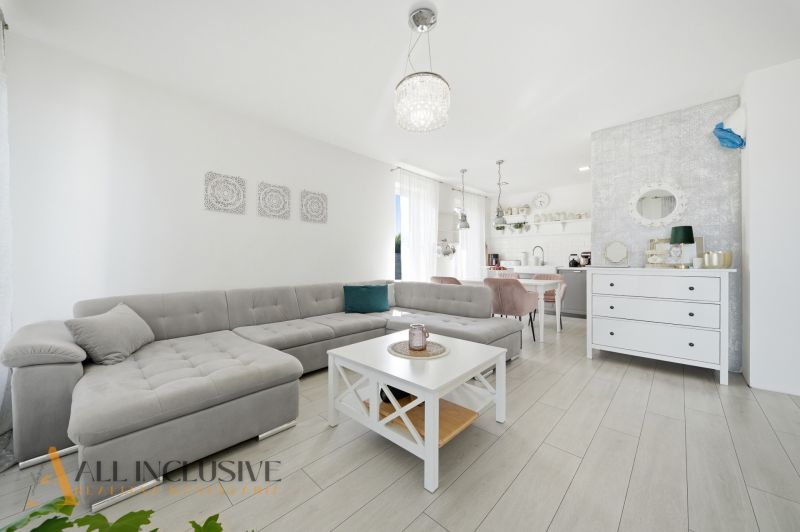 Living room with a corner sofa, table, and wooden decor flooring in a family house.