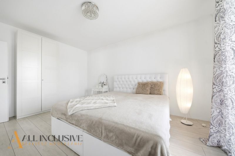 A bedroom with white furniture and a bed in a family house, floor with wooden decor.