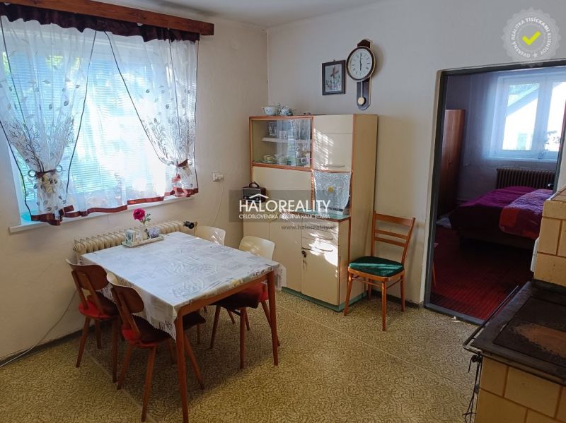 Dining room in a family house with vintage furniture, floral decorations, and a passage to the bedroom.