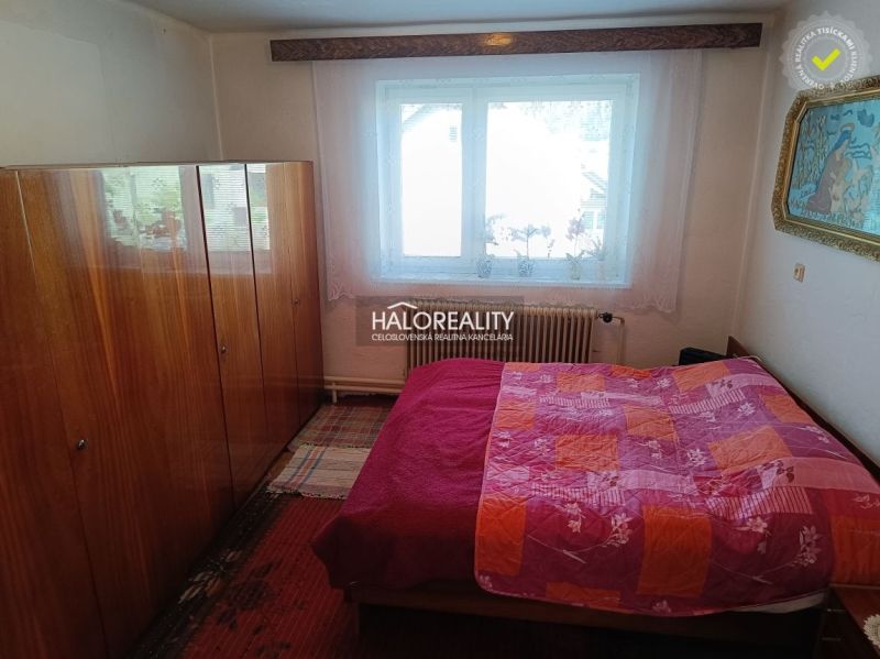 Bedroom in a family house with a bed, wardrobe, and window. It has a floor with a wooden decor.