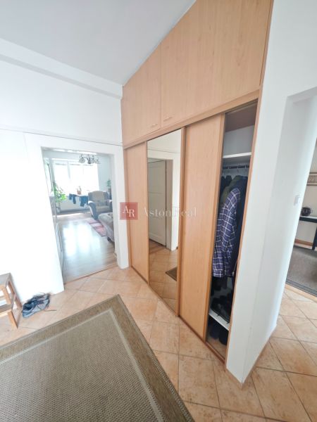 Built-in wardrobe and tiles in the hallway of a 2-room apartment with a wooden decor floor.