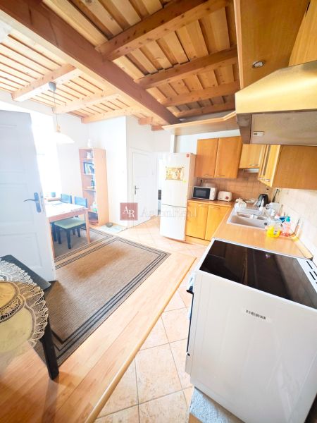 A kitchen in a 2-room apartment with a wooden decor floor and a wooden ceiling.