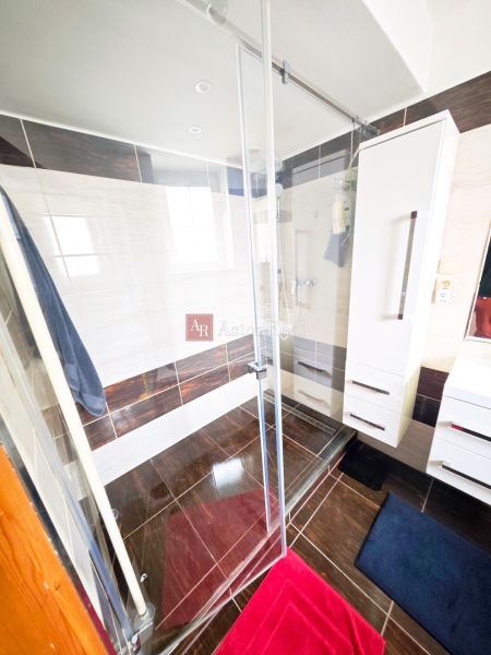 Bathroom in a 2-room apartment with a shower and a floor with a wooden decor.