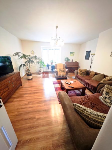 Living room in a two-room apartment with a wooden decor floor and a comfortable sofa.