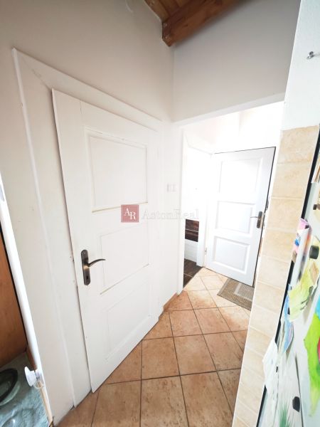 Hallway in a 2-room apartment with ceramic tiles and white doors.