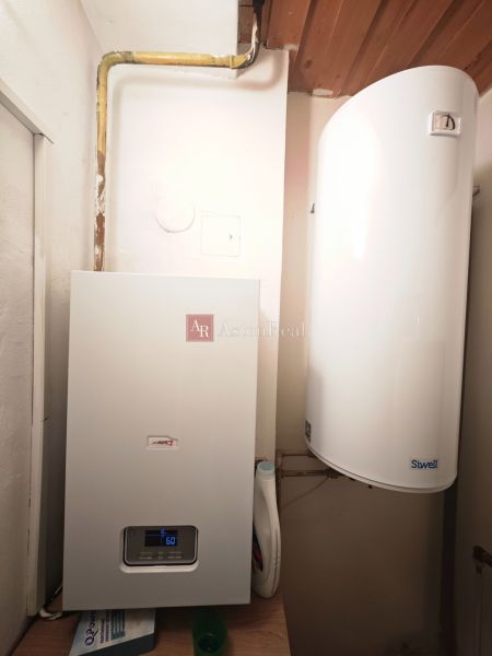 Heating appliances in the bathroom of a two-room apartment with a wooden decor floor.