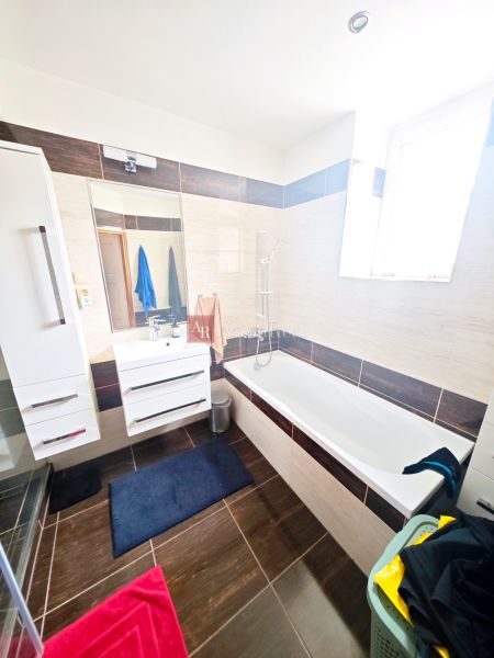 A bathroom in a 2-room apartment with a bathtub, shower, and white furniture.