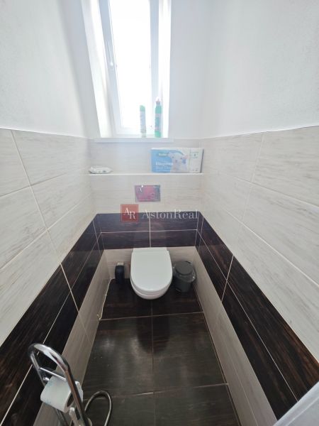 Bathroom with toilet in a 2-room apartment, tiles with wood decor on the walls.