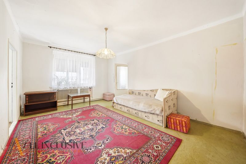 Living room in a family house with a carpet and a sofa, simple interior.