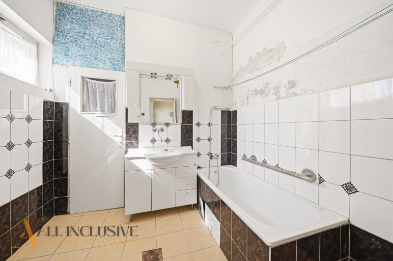A bathroom in a family house with a white bathtub and mosaic tiles.