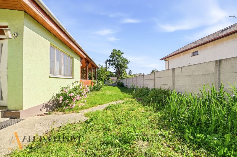 A garden at a family house in Hviezdoslavov with a lawn and flowers, bordered by a fence.