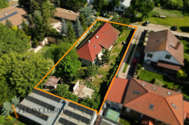 A family house in Hviezdoslavov with a red roof, surrounded by greenery and other buildings.