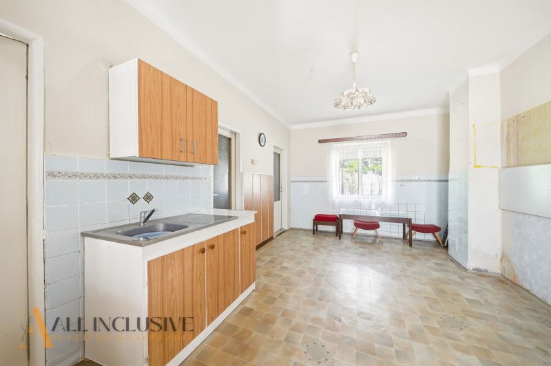 A kitchen with wooden cabinets and tiles, in a family house.