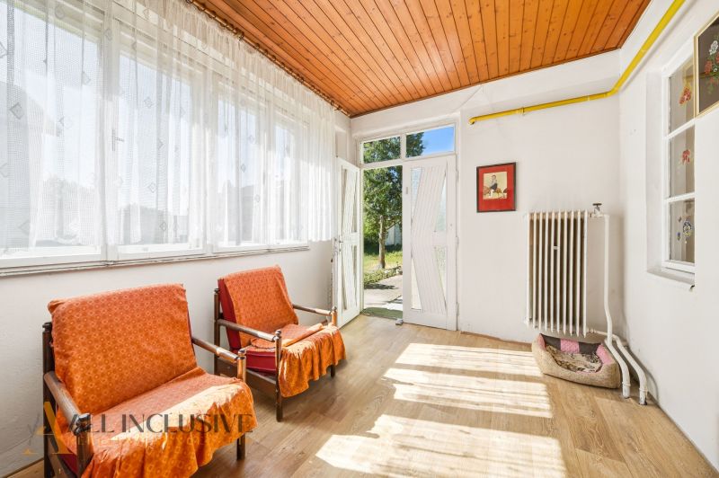 Interior of a family house with armchairs, large windows, and a wooden decor floor.