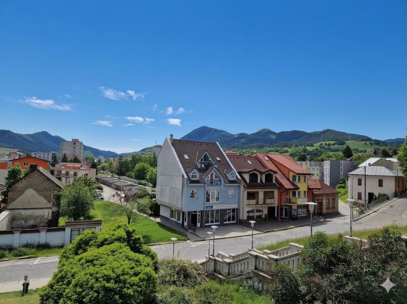 A view of buildings and streets in Ružomberok, with green hills in the background.