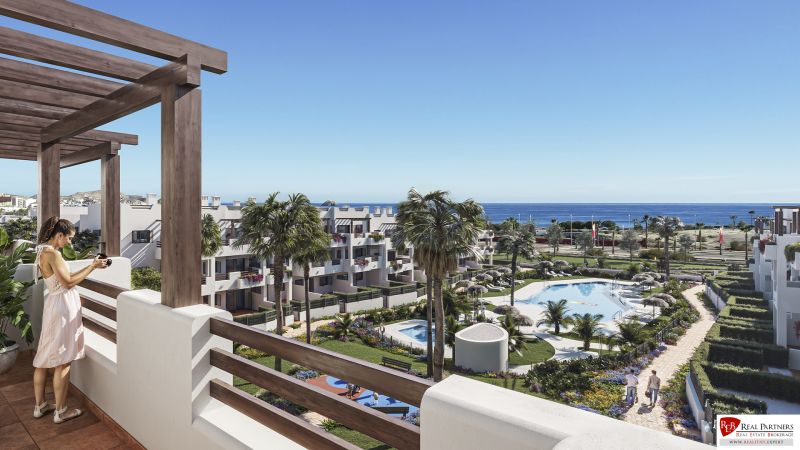 Balcony of a holiday apartment in Pulpí with a view of the pool and sea, surrounded by palm trees.