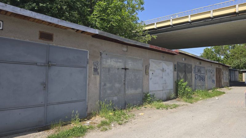 Garages on Jesenského Street in Zvolen along the road with greenery and graffiti.