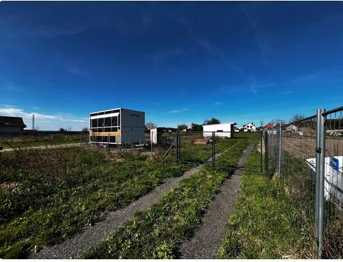 Land - housing in Pernek with containers, fences, and a grassy road in the countryside.