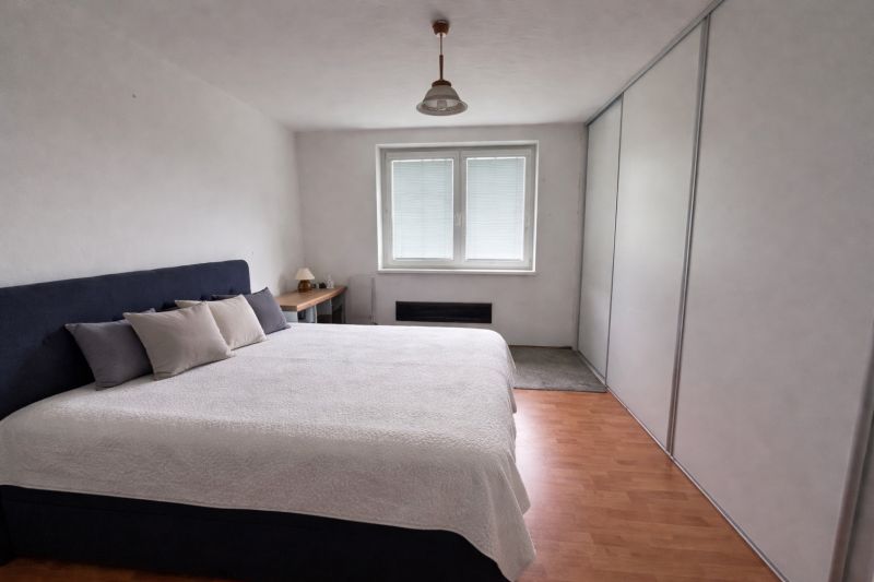 Bedroom with a large bed and a wooden decor floor in a family house.