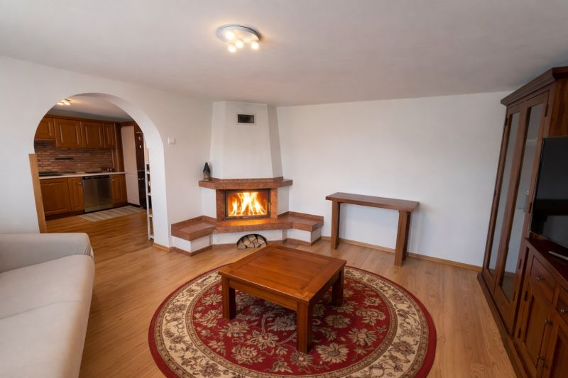 Living room in a family house with a fireplace, wooden decor flooring, and an arched doorway.