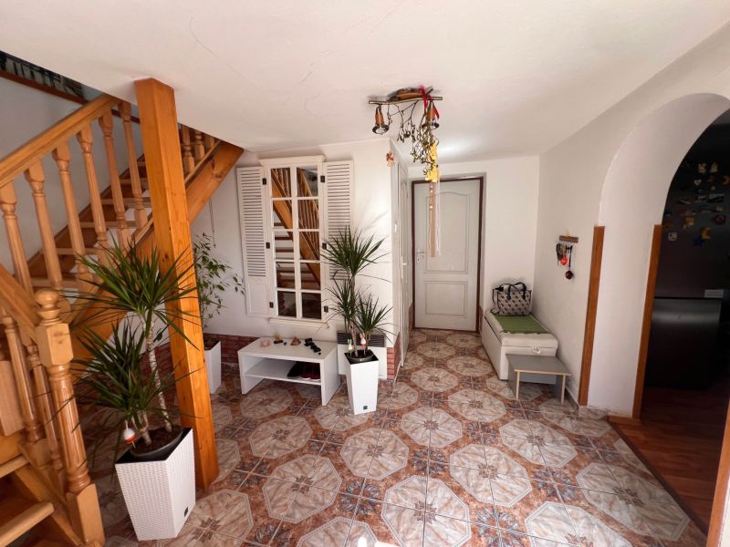 Interior of a family house with a staircase, plants, and tiles with a warm-colored decor.