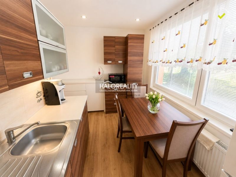 A kitchen in a studio apartment with wooden decor, a dining table, and a sunny window.