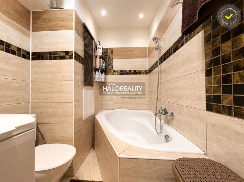 Bathroom with a bathtub, modern tiles, and a toilet in a studio apartment.