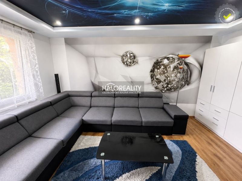 Living room in a one-bedroom apartment with a corner sofa, wooden decor flooring, and a decorative ceiling.