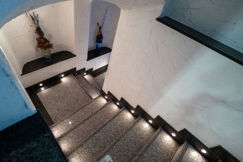 A staircase with lighting, decorated with vases, textured walls in a peculiar property.