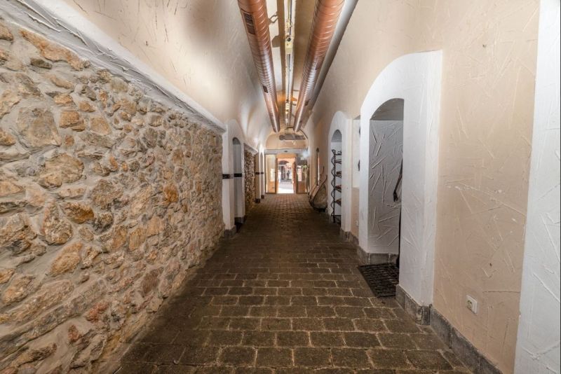 A corridor with a stone wall and an arched ceiling in Strange Properties.