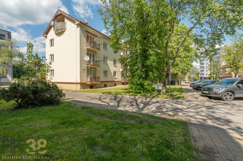 The exterior of a building with a 3-room apartment in Poprad, surrounded by greenery and a parking lot.