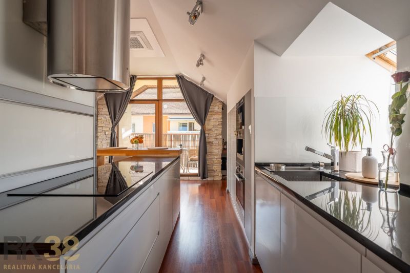 A kitchen in a 3-room apartment with a wooden decor floor, bright, with a plant and a cooktop.
