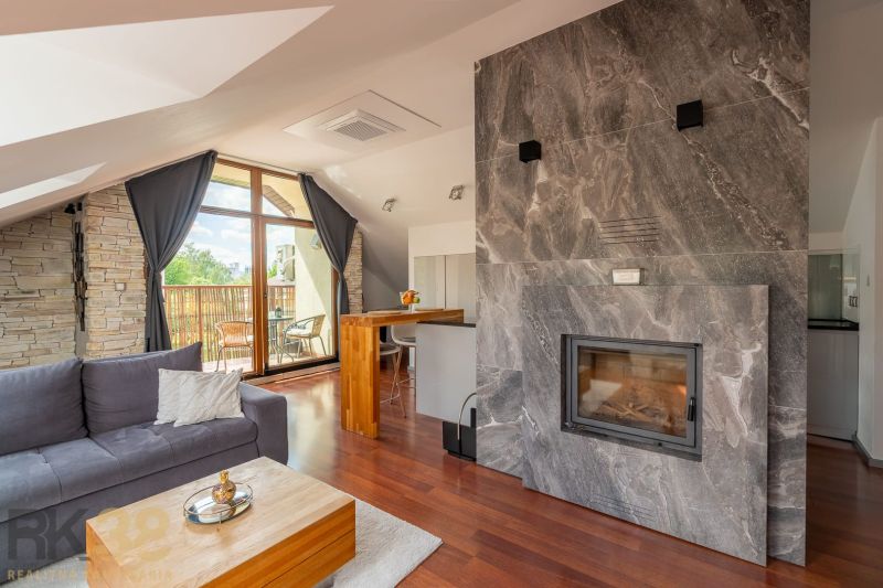 Living room of a 3-room apartment with a sloped ceiling, fireplace, and wood-patterned flooring.