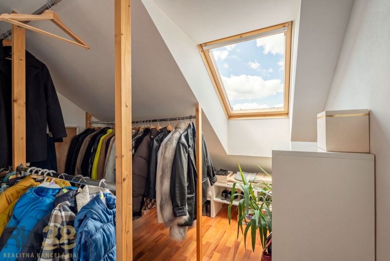 Attic wardrobe with a wooden decor floor in a 3-room apartment with a skylight.