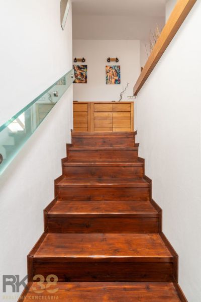 Stairs with a wooden decor floor and glass railing in a 3-room apartment.