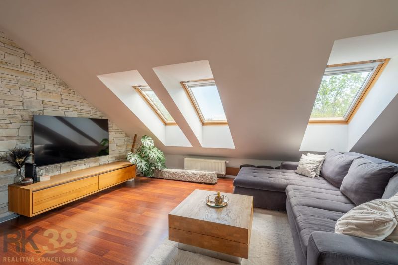 Attic living room in a 3-room apartment with a corner sofa and a wooden decor floor.