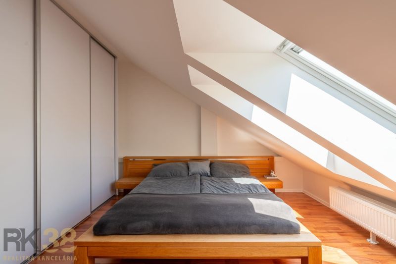 A bedroom in a three-room apartment with a wooden decor floor and skylights.