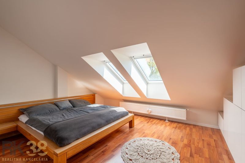 Attic bedroom in a 3-room apartment with wood-patterned flooring and skylights.