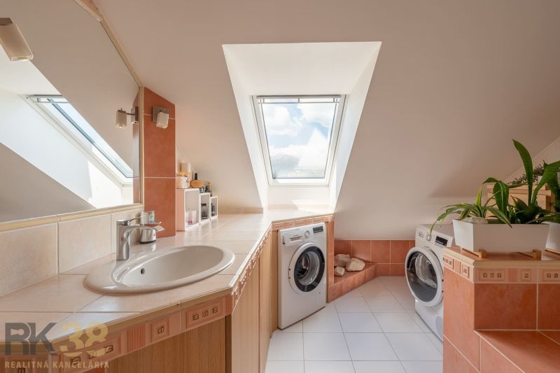 A bathroom in a 3-room apartment with a washing machine, a skylight, and white tiles.