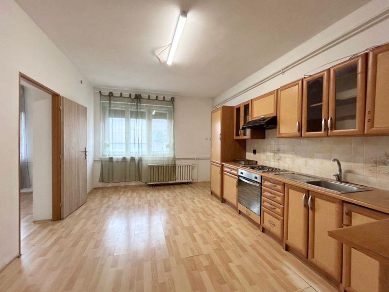 A kitchen in a family house with a light-colored kitchen unit and a wooden-patterned floor.