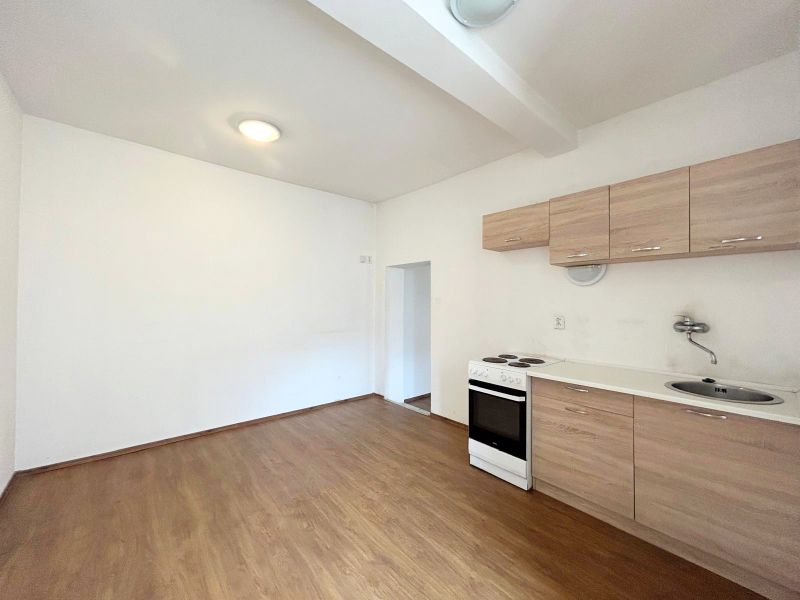 A kitchen in a family house with a simple kitchen unit and a wooden decor floor.