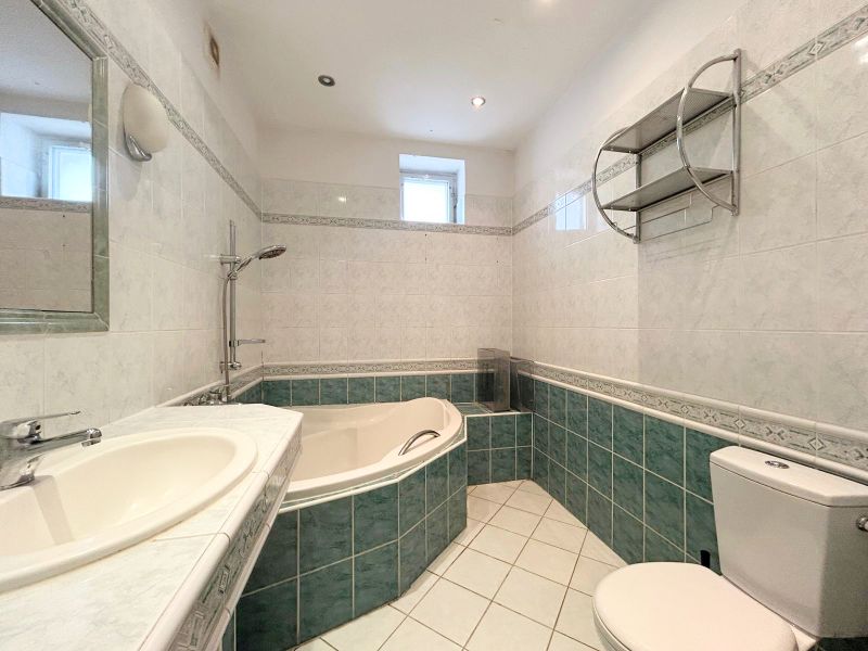 A bathroom in a family house with a bathtub, sink, mirror, and toilet.