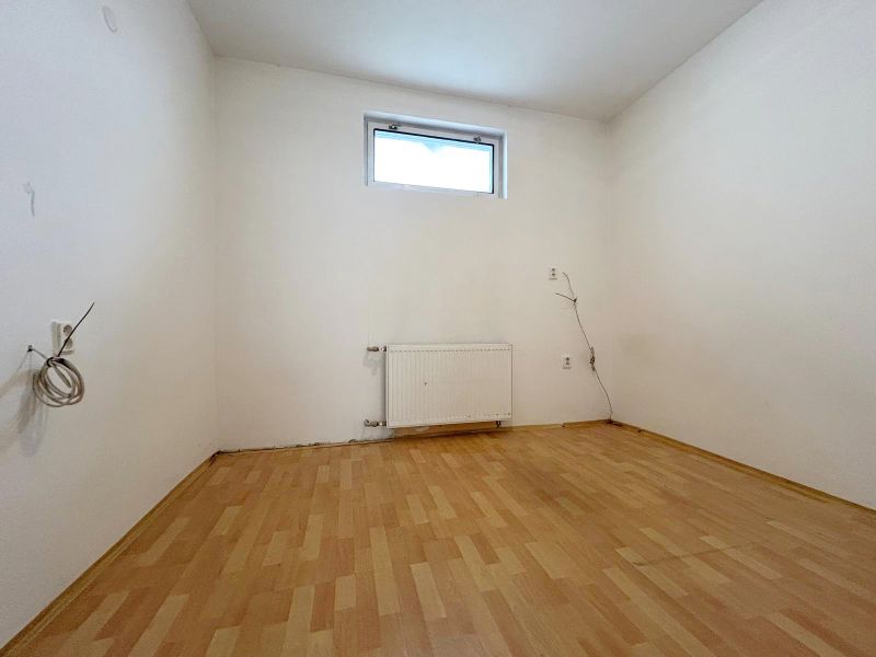 A room in a family house with a wooden decor floor and a radiator under the window.