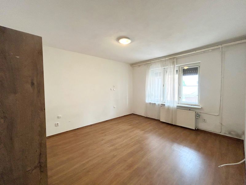 A room in a family house with a wooden decor floor and windows with white curtains.