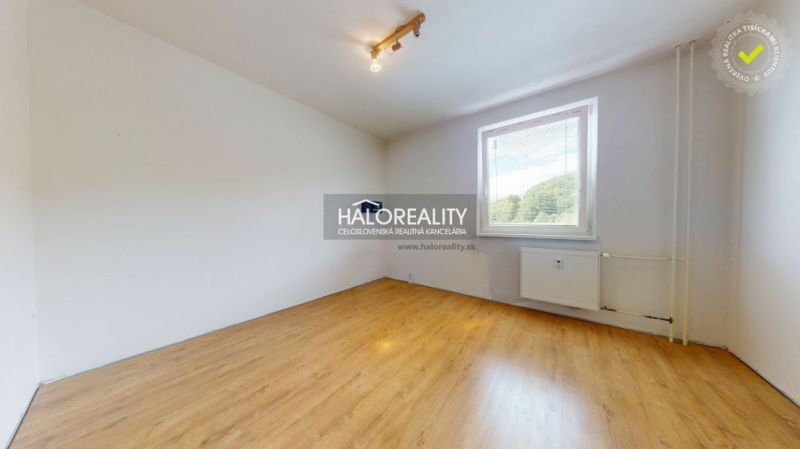 A room in a three-room apartment with a wooden decor floor and a large window.