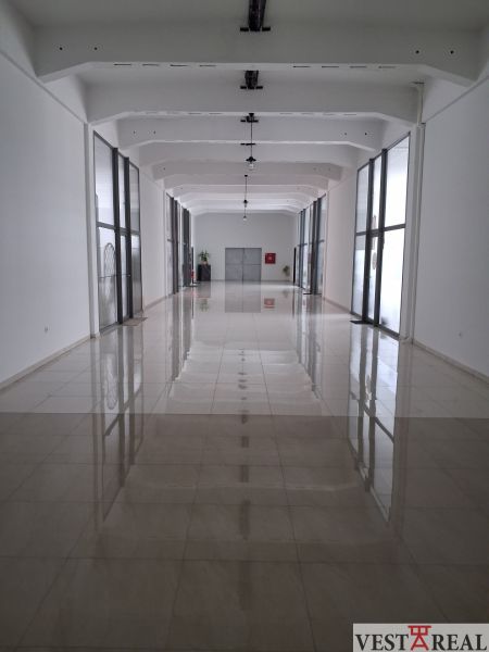 A spacious hallway in offices with a shiny floor and glass walls.