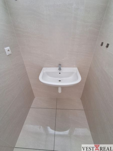 A sink in the office on light tiles with a glossy floor.